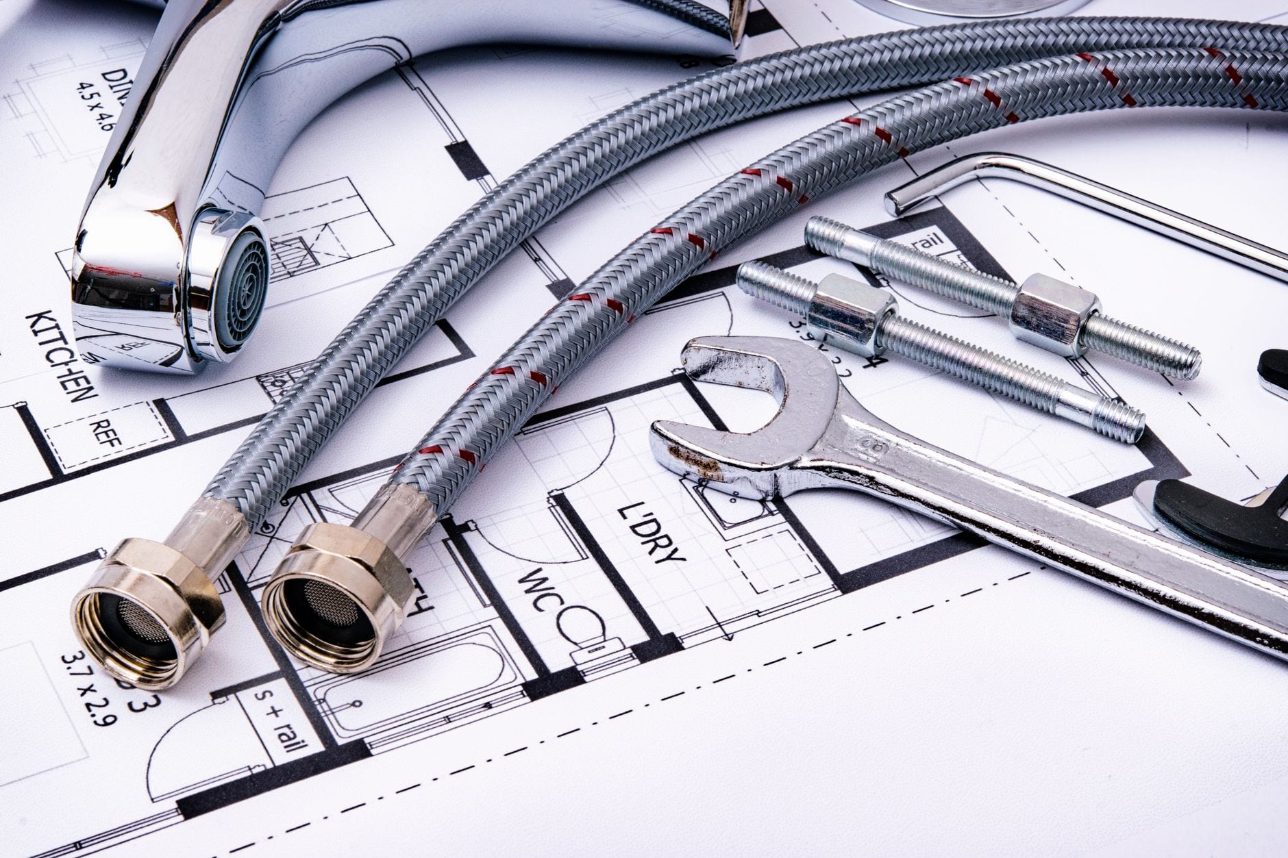 Plumbing fittings and a wrench laid out on a floor plan blueprint